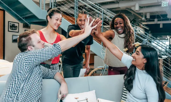 Diverse group of colleagues smiling and giving high fives in a team setting